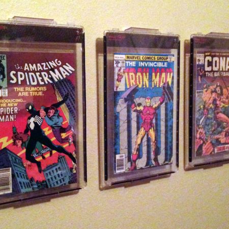 A wall with three comic books hanging on it.